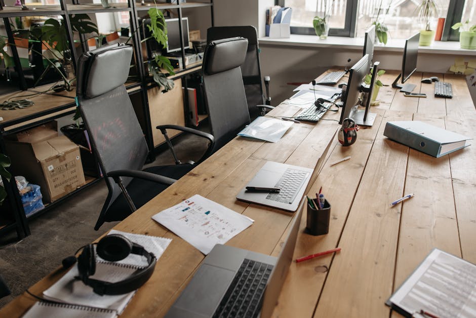 Spacious co-working office with wooden desks, laptops, and modern chairs.